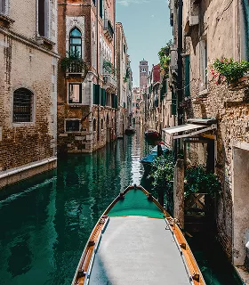 A gondola floats on a narrow, calm canal in Venice, flanked by historic buildings