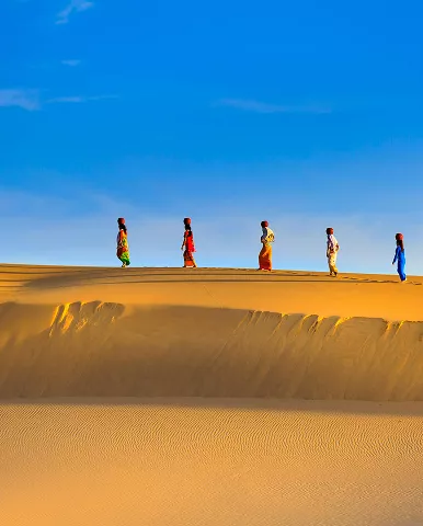 A group of people walking together across a sandy dune