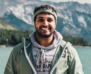 A man in a green jacket and hat stands confidently