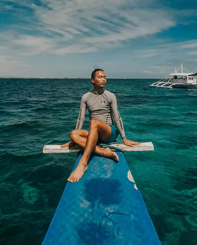 A man sitting on a surfboard, surrounded by ocean waves under a clear blue sky