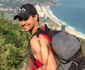 A man wearing a backpack stands outdoors