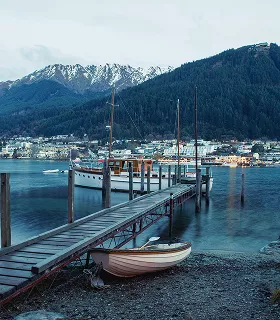A serene lakeside scene at dusk with a wooden pier and boats