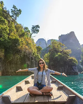  A woman sitting on a boat, enjoying the view of the water and surrounding landscape