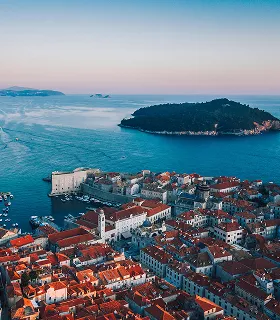 Aerial view of a coastal city with terracotta rooftops and narrow streets