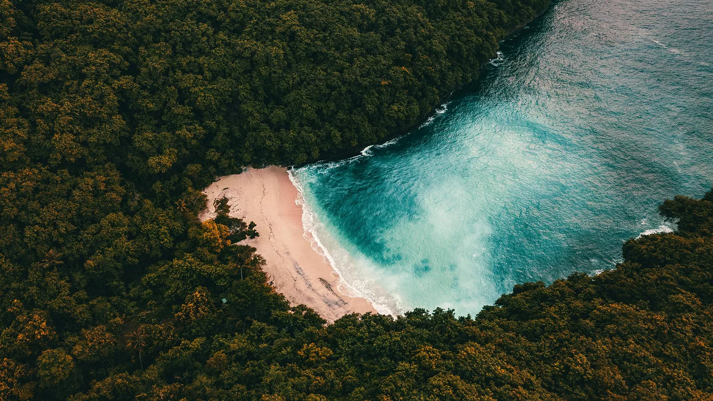 Two people sit on rocks beside a cascading waterfall