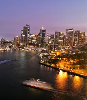 City skyline at dusk with illuminated skyscrapers reflecting on water