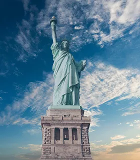 The Statue of Liberty against a vibrant blue sky with wispy clouds
