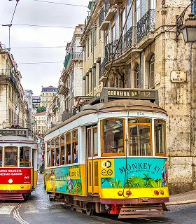Vintage yellow and red trams navigate a narrow, cobblestone street